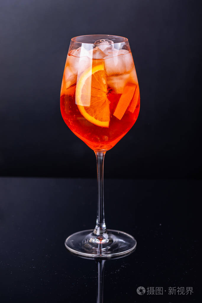 在黑色反射背景上的玻璃中的一杯淡紫色鸡尾酒