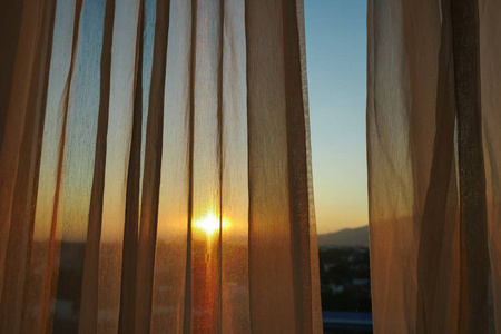 阳光透过窗户内部的白色窗帘照片