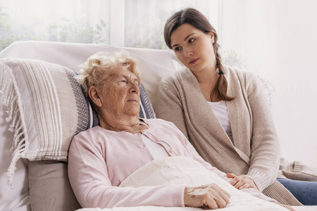 小女儿扶着躺在病床上的生病母亲照片