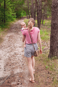 背影年轻父亲和他可爱女儿的背影母亲带着女儿走在乡间小路上,背景是