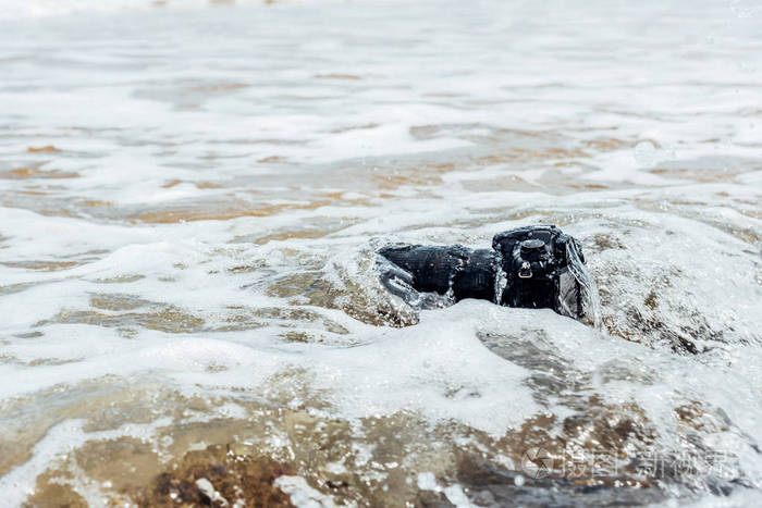 被海浪打湿的石头海滩上的数码单反相机