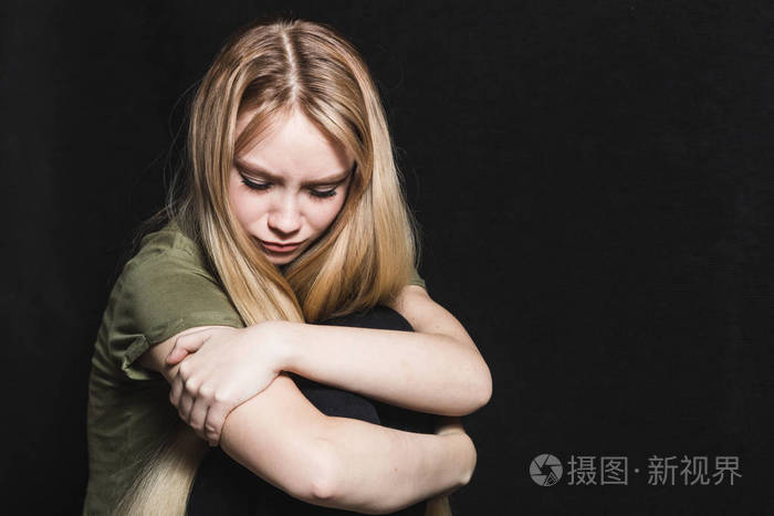 悲伤的年轻女人要在黑色背景下哭泣