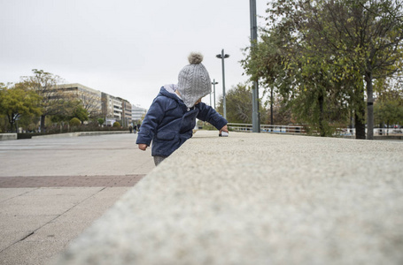 小孩开抽屉一个蹒跚学步的小孩在外面的水泥长凳上开着他的玩具车照片