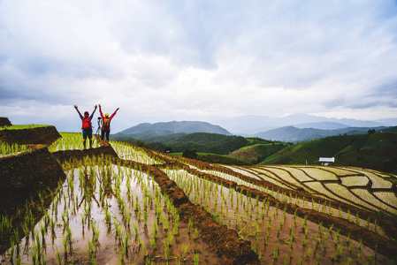夫妻合影旅游自然爱好者亚洲女人和亚洲男人在雨季的田野上散步合影.