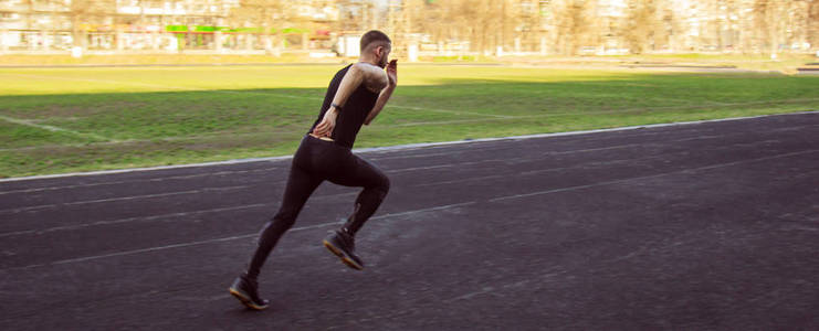 一名白人男子正在进行短跑起跑.在体育场的橡胶跑道上跑步.