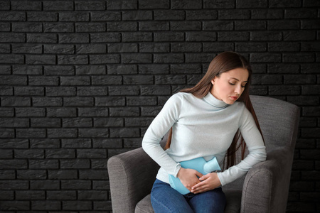 椅上腹痛的妇女手放在肚子上的女人,腹痛女性生殖器官美丽的艺术设计