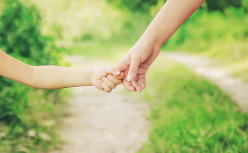妈妈和女儿手牵着手走在路上.照片