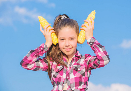 素食营养理念.小女孩拿着黄色的玉米芯在天空背景上.