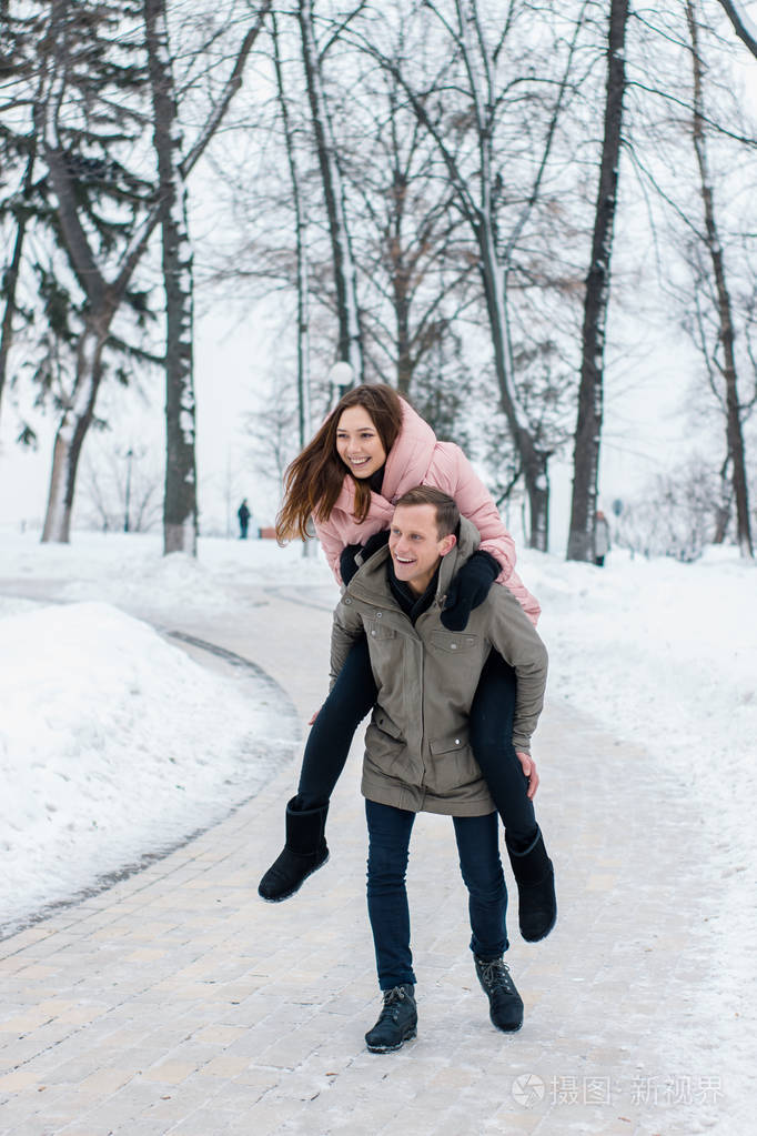 一对快乐的冬季旅行者一个女人在冬天的雪林里骑着一个男人