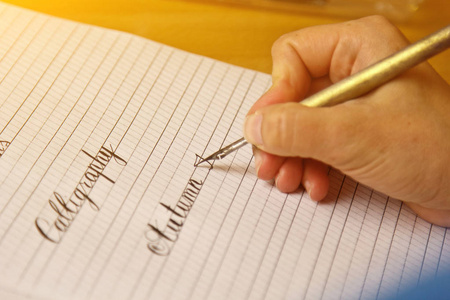 女性用墨水笔在有条纹的白纸上写字.办公桌上的文具特写俯视图.