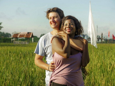 儿夫妇与黑人黑人美国妇女和迷人的白人男子拥抱在稻田里享受假期照片