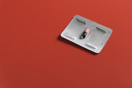 选择平板电脑治疗维生素唯一一颗红色背景水泡里的药丸.复制空间.