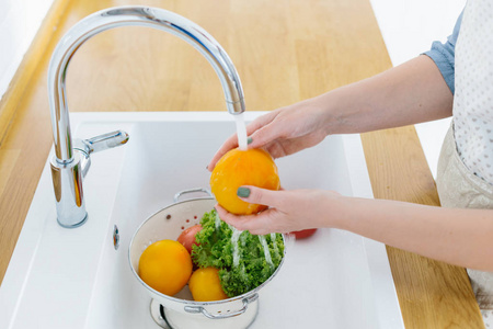 用白色洗新鲜蔬菜手洗蔬菜的女人.
