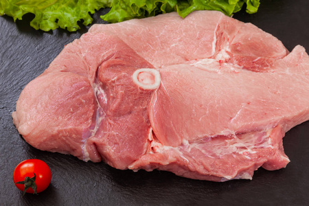 黑盘子里的一块猪肉照片