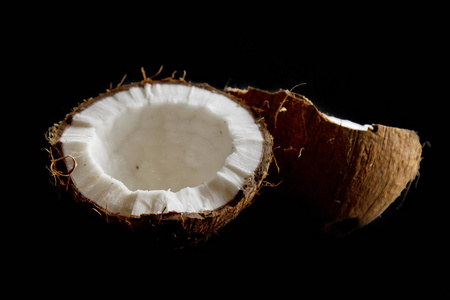 在黑色背景特写镜头中,成熟的椰子被分成两半.热带棕榈胎儿的内部照片