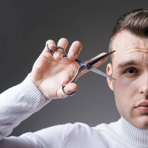 男子严脸拿剪刀理发师光面发型手持钢剪刀创造你的风格
