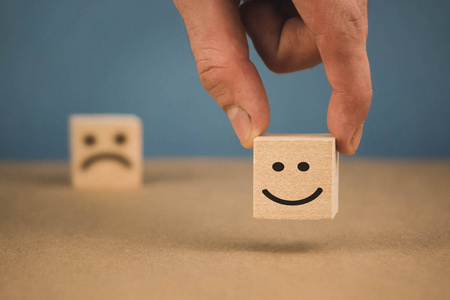 坚决表情有微笑表情和悲伤表情的木块.照片