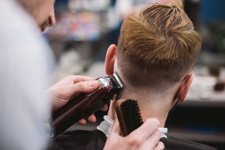 男发型师为客户服务,使用机器和梳子理发照片