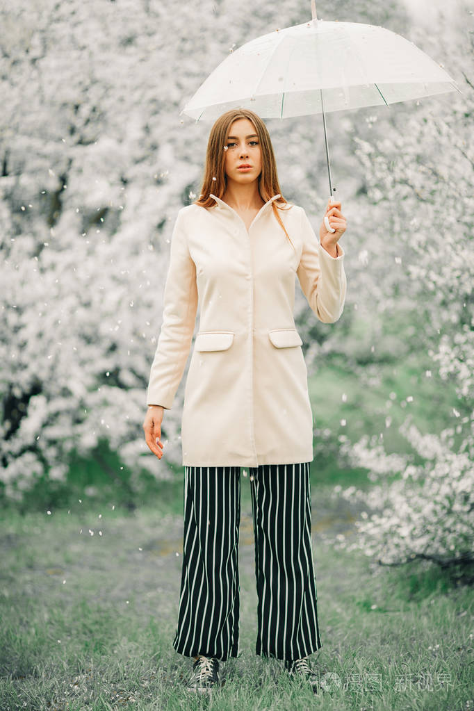 一个女人手里拿着雨伞在春天的花园里放松