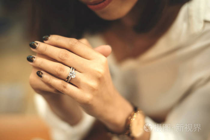 一个优雅的订婚钻戒在女人手指上的特写镜头，深粉色毛衣冬装。爱情和婚礼概念。