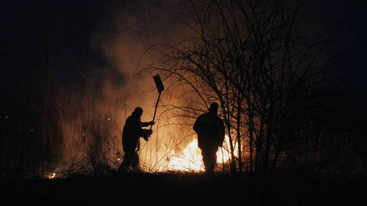 森林防火人人有责两名消防队员用防火挡板在夜间扑灭森林里的火照片