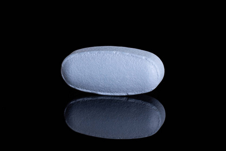 抗焦虑治疗黑色玻璃上隔离的蓝色药丸照片