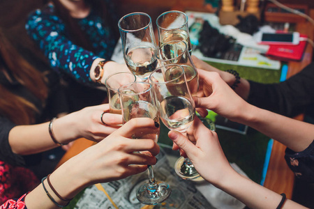 正在用香槟酒杯碰杯一群兴高采烈的年轻人正碰着香槟酒杯手举酒杯敬酒
