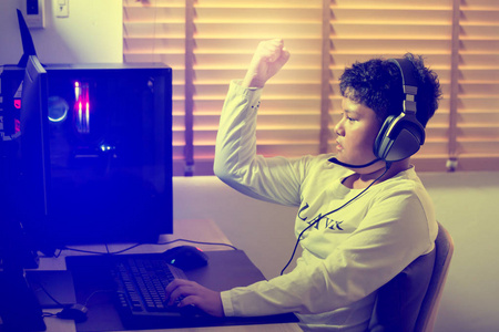 在家里用电脑玩游戏的亚洲男孩照片