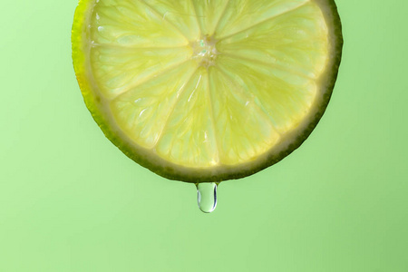 水滴状的水果绿色背景下,从一片石灰中流出的水滴状果汁.照片