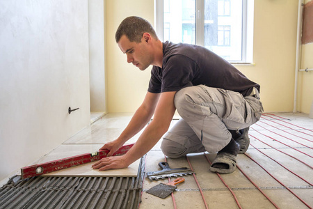 年轻工人用杠杆安装瓷砖图片