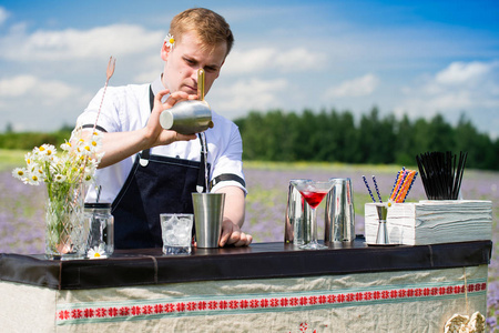 酒保的工作在出发.帅气的调酒师在户外准备鸡尾酒照片