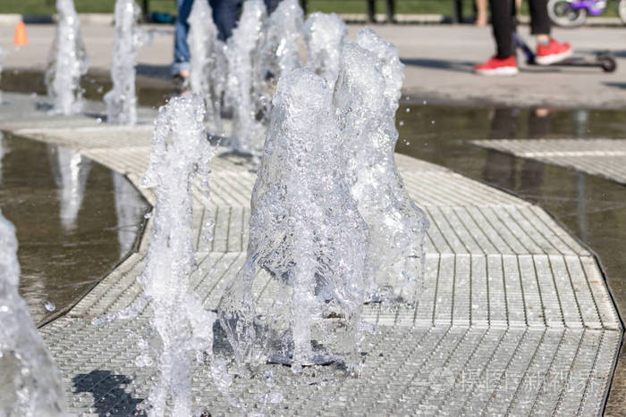 城市喷泉的水流飞溅水柱中的泡沫城市公园游憩区碎片