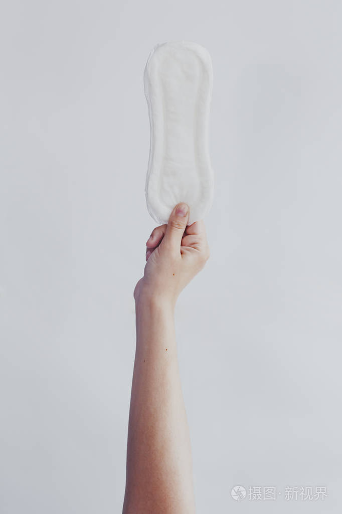 女人在白色背景下挂卫生巾月经日概念显示女性月经周期