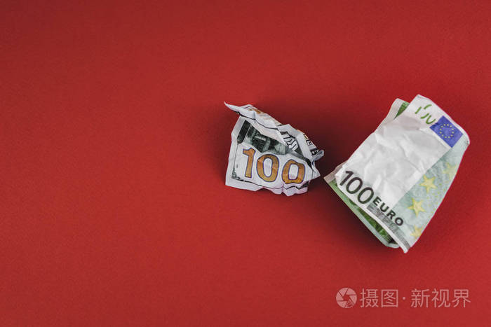 红色背景上皱巴巴的一百欧元和美元钞票
