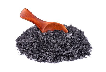 黑海盐放在木勺里,白底隔离.晶体中的火山盐.照片