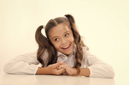 女生快乐无忧无虑的脸上可爱的马尾辫.优秀小学生靠在桌子上照片