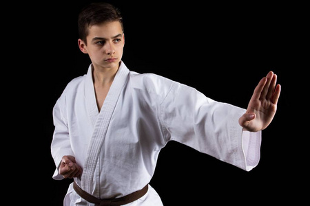 空手道武术运动与年轻男孩和服,黑色背景,活动.照片