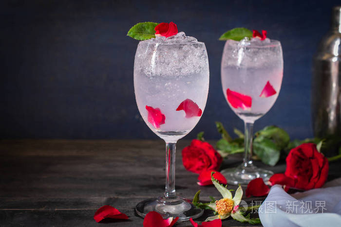 用玫瑰和冰块在木桌上放有玫瑰同样的东西和鸡尾酒摇篮放在周围