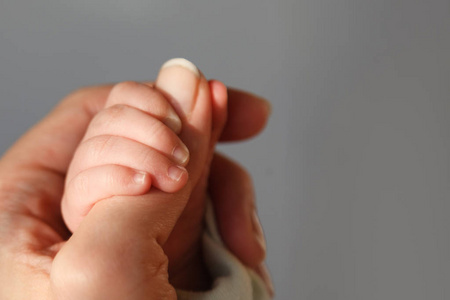 妈妈牵着宝宝新生婴儿牵着妈妈的手.爱与家庭观念.照片