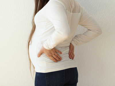 往后一个穿着白色衣服的大肚子的怀孕女孩站在那里,把她往后拉照片