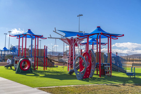 阳光明媚的孩子们在草坪上投下阴影的多彩游乐场照片