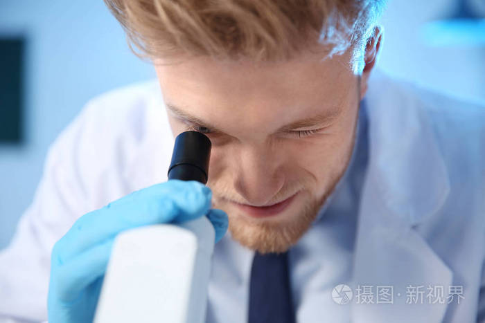 男科学家在化学实验室使用现代显微镜