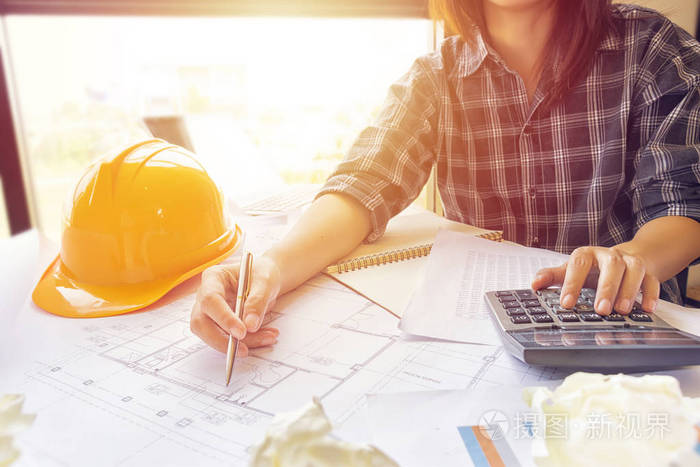 亚洲工程师女建筑师在办公室工作场所在电脑笔记本电脑前用计算器计算