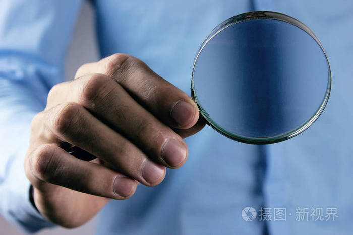 男人手里拿着放大镜照片-正版商用图片2jg52a-摄图新视界