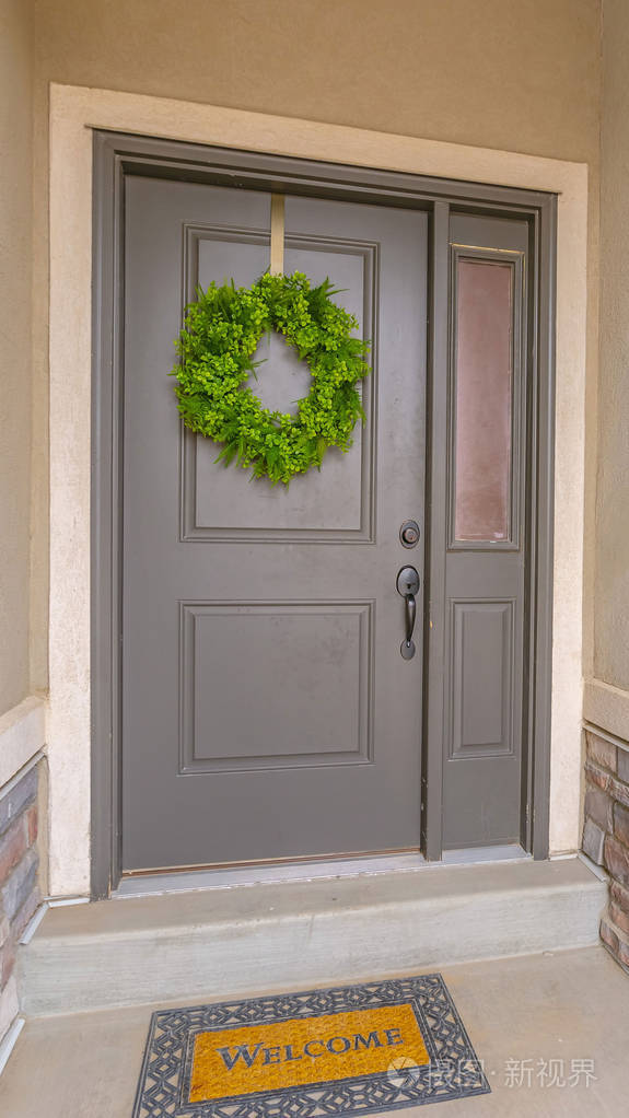 一个带有简单的绿色花环和侧灯的垂直灰色家门