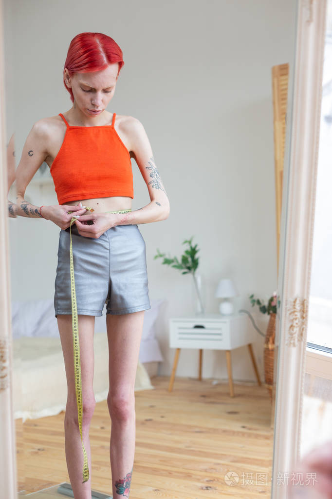 瘦骨嶙峋的女人用卷尺量腰围照片-正版商用图片2jivta-摄图新视界