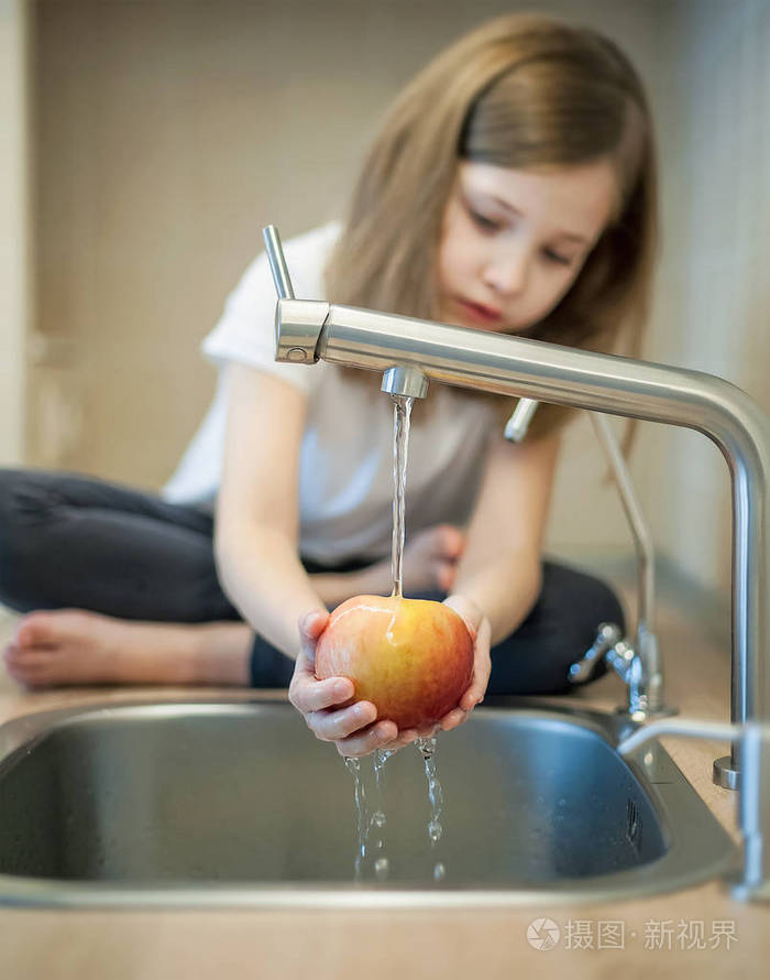 一个可爱的小女孩在水槽里洗红黄色的苹果孩子正在厨房里洗水果小孩子