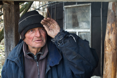 在门槛上一位衣衫褴褛的老人站在自家被毁房屋的门槛上,向远处张望