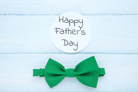 木桌上戴绿色领结的父亲节快乐图片
