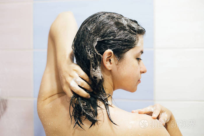 年轻快乐的女人用洗发水洗头用透明质酸起泡